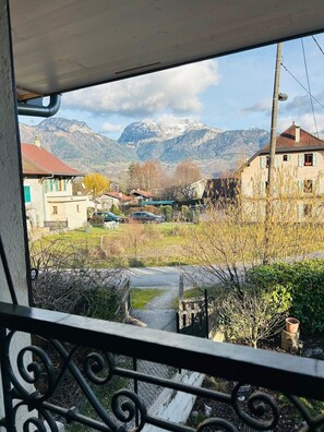A balcony with a view of a village, houses, and mountains.