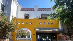 Un edificio con fachada amarilla, una entrada arqueada grande y un portón negro.
