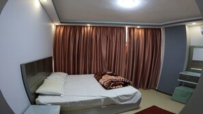 Relax in a clean and minimalist space with a comfortable bed, bedside table, and large window.