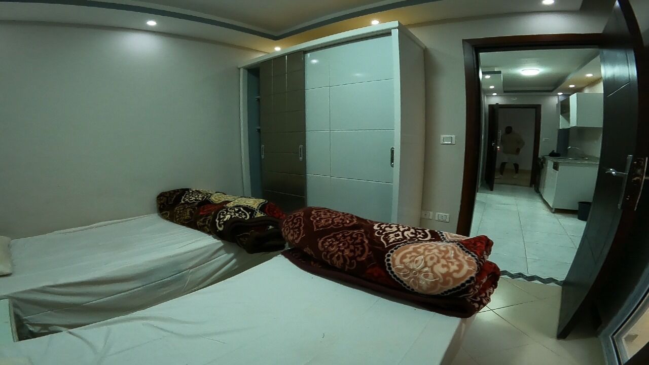 A bedroom with two beds, a wardrobe, and a mirror.