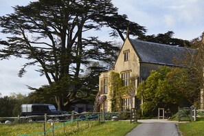 A stone building with a steep roof, large windows, and a pathway leading to the entrance. - THE PIG at Combe - Devon (Honiton)
