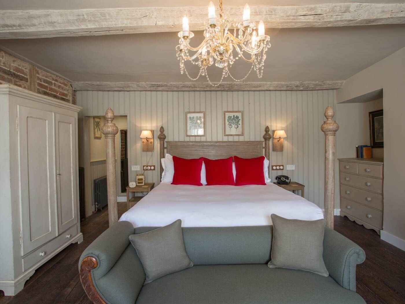 A spacious bedroom with a large bed, a chandelier, and a cozy seating area.