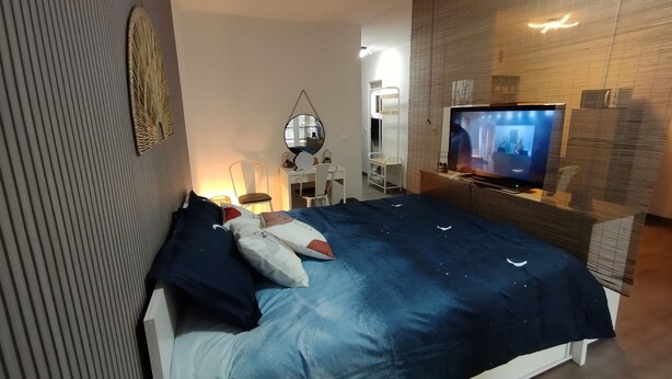 Ein Schlafzimmer mit Bett, Fernseher, Schreibtisch und Stuhl.