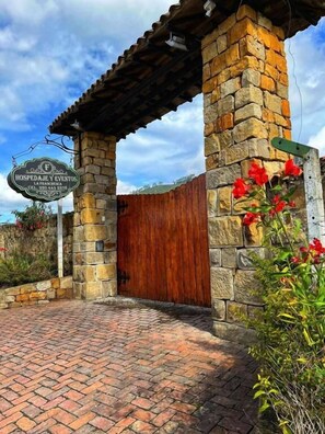 A stone building with a wooden door and a sign that reads "HOSPEDALJE Y EVENTOS". - Hotel Campestre Franchesca (Tenjo)