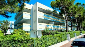 A multi-story building with balconies, surrounded by greenery and trees. - Delightful Seaside Flat With ac - Beahost (San Michele al Tagliamento)