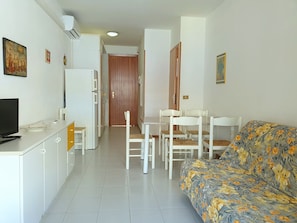 A compact living space with a kitchenette, a dining area, and a sofa. - Delightful Seaside Flat With ac - Beahost (San Michele al Tagliamento)