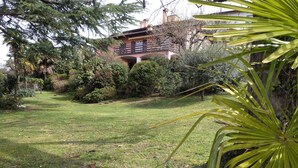A well-maintained garden with a pathway leading to a building with a balcony. - 3 minutes from the lake, with a large terrace and garden (Leggiuno)