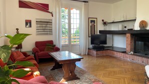 Un salon avec un canapé rouge, une table basse en bois, une cheminée et un téléviseur.