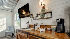 A kitchen with a wooden countertop, a coffee maker, and a television mounted on the wall. - Windmill Meadows Cottages-firepit-hill Country Views!! (Harper)