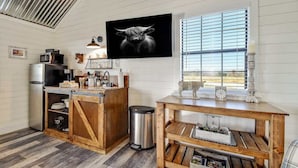 A kitchen with a wooden island, stainless steel appliances, and a large window with blinds. - Windmill Meadows Cottages-firepit-hill Country Views!! (Harper)