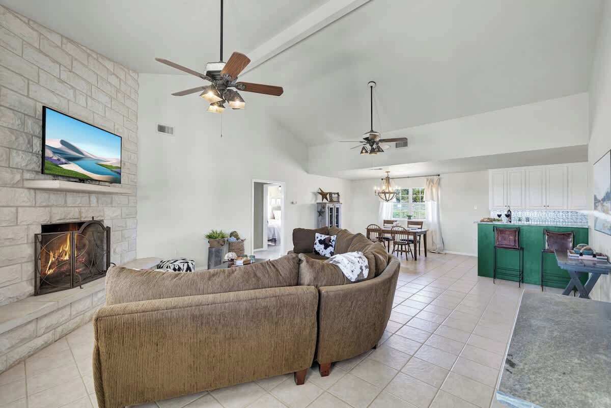 A spacious living room with a sectional sofa, fireplace, ceiling fans, and a dining area.