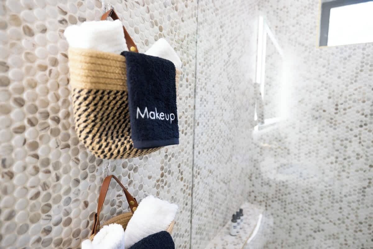 A bathroom with a textured wall and a towel rack holding a black towel labeled "Makeup."