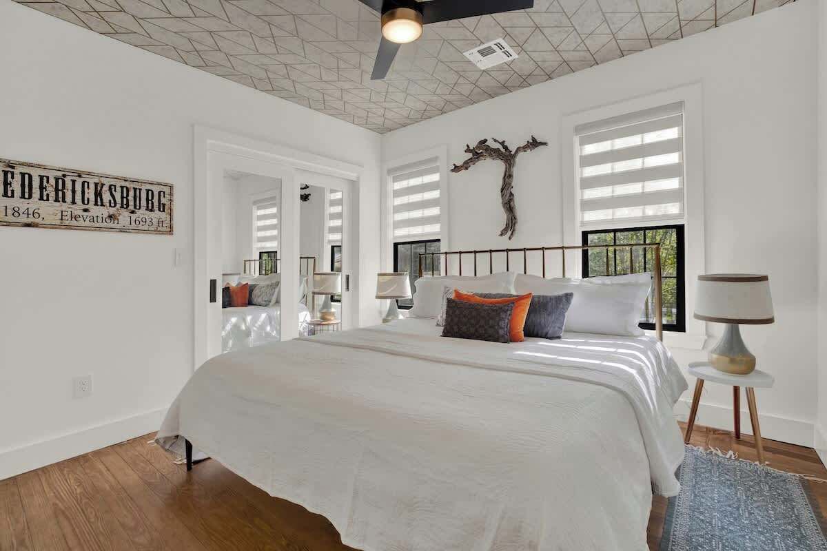 Un dormitorio con una cama grande, un ventilador de techo, una escultura de árbol montada en la pared y un cartel con información histórica.
