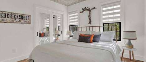 Un dormitorio con una cama grande, un ventilador de techo, una escultura de árbol montada en la pared y un cartel con información histórica.