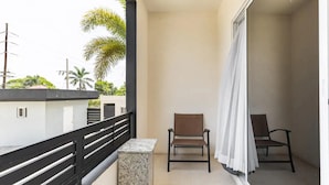 A balcony with two chairs, a small table, and a white curtain. - Apt - Gated Community-sleeps 4-balcony-parking (Runaway Bay)