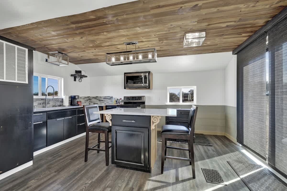 Una cocina moderna con techo de madera, armarios negros y una isla central con taburetes de bar.