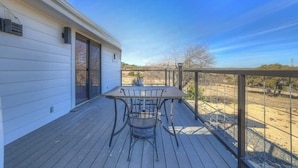 A wooden deck with a table and chairs, overlooking a landscape with trees and a clear sky. - K Loma Vista With Hill Country Views (Center Point)