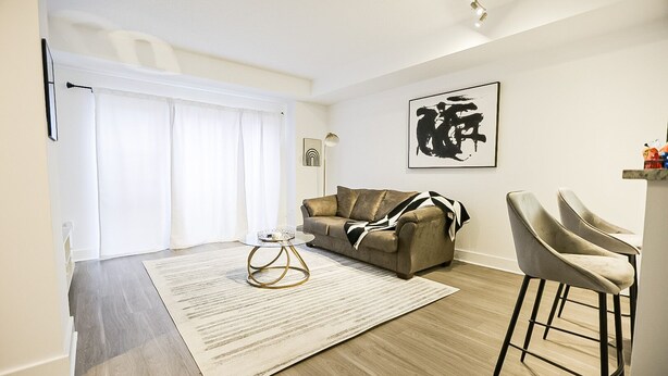 Un salon moderne avec un canapé, une table basse et un tabouret de bar.