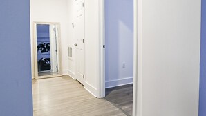 Un couloir doté d’un parquet en bois clair, de murs blancs et d’une porte donnant sur une pièce avec vue.