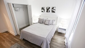 Une chambre à coucher comprenant un lit, des tables de chevet, une armoire et des œuvres d’art abstraites accrochées au mur.
