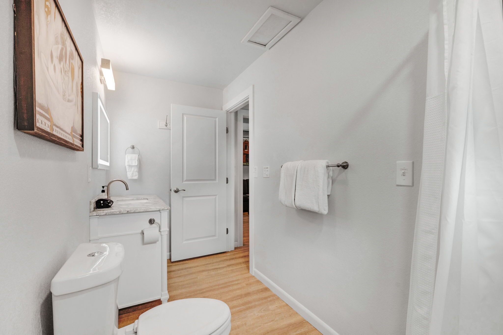 Une petite salle de bain propre, équipée de toilettes, d’un lavabo et d’un porte-serviettes.