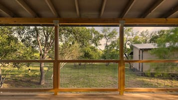 A wooden deck with a view of a grassy yard and trees.