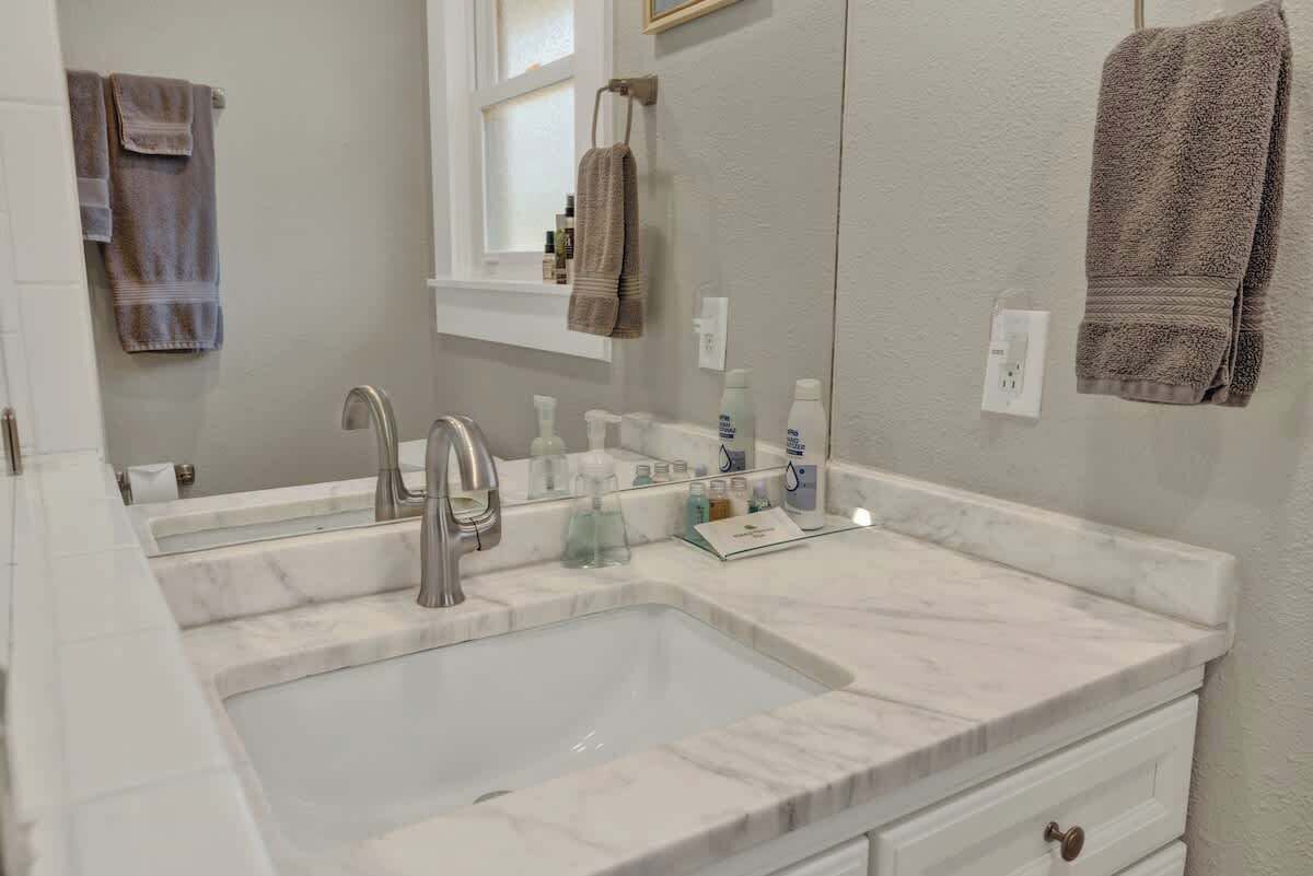 A bathroom with a large mirror, two sinks, and a window above the sink.