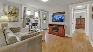Ein Wohnzimmer mit einer Couch, einem Fernseher, einem Kamin und einem Essbereich.