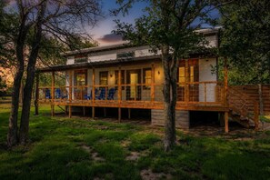 A two-story wooden house with a covered porch and a staircase. - Primrose Waterfront With Hot Tub (Fredericksburg)