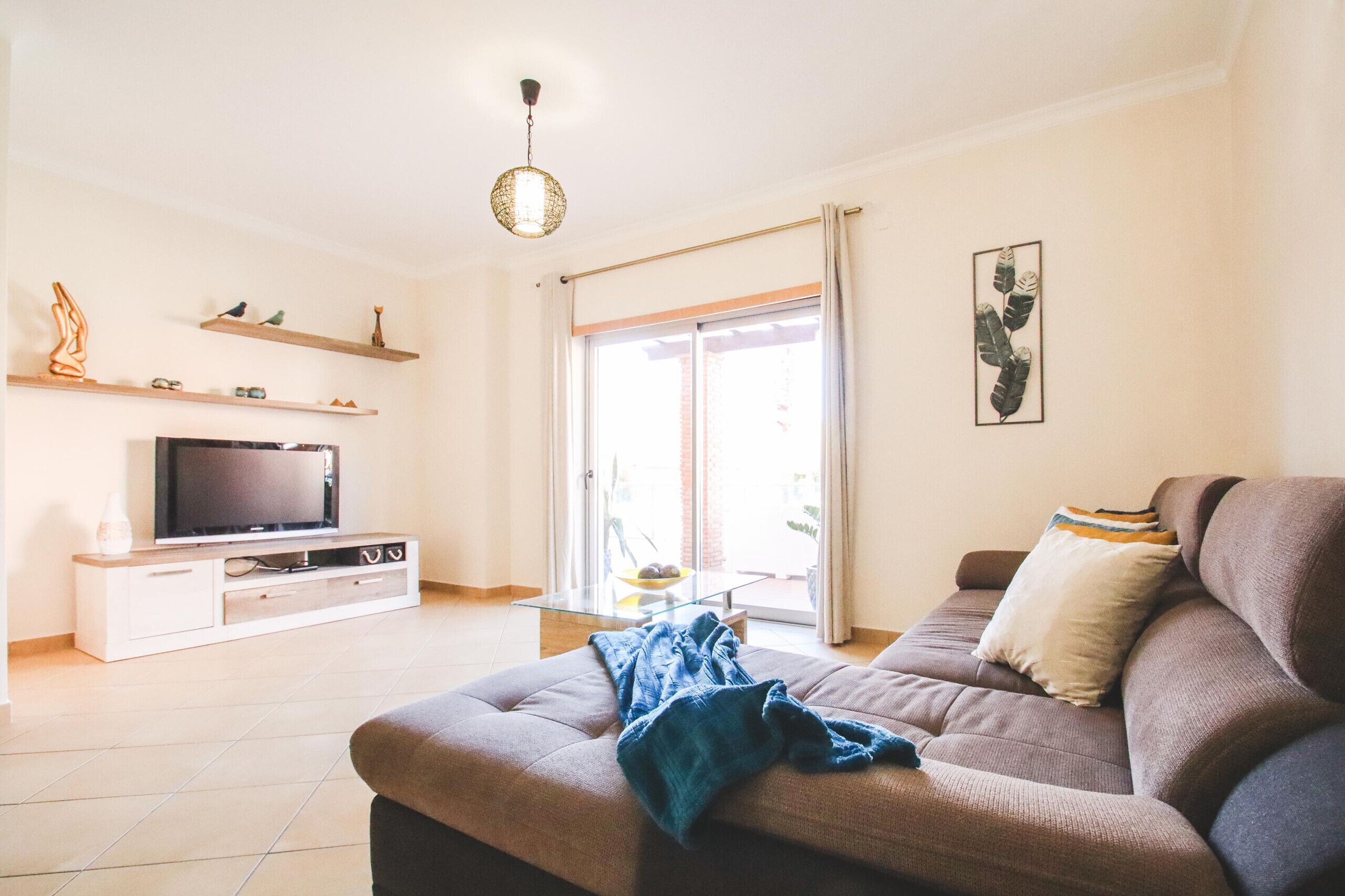 Una sala de estar con sofá, televisión y estanterías.