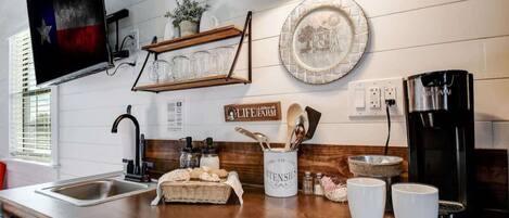 A kitchen with a wooden countertop, a coffee maker, a sink, and a sign that reads "LIFE FARM".