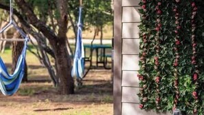A porch with a hammock and a neon sign reading "Rivers Edge Cottages". - Winecup Waterfront Cottage (Fredericksburg)