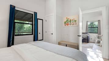 Une chambre à coucher avec un lit, un banc, une porte et une fenêtre.