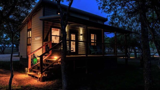 A cabin with a staircase, large windows, and a porch. - Winecup Waterfront Cottage (Fredericksburg)