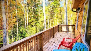 Eine Holzterrasse mit Geländer, zwei Stühlen und einem Blumentopf.