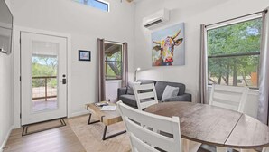 Un salon moderne comprenant une table à manger, un canapé, un ventilateur de plafond et une grande fenêtre.