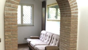 Un canapé beige dans une pièce aux murs en briques et dotée d’une fenêtre.