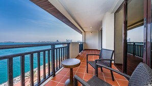 A balcony with a view of the sea and city skyline, featuring a table and two chairs.