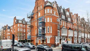 A row of red brick buildings with white trim and multiple windows, some with bay windows. - Stunning 3 bed flat in the heart of Chelsea (London)
