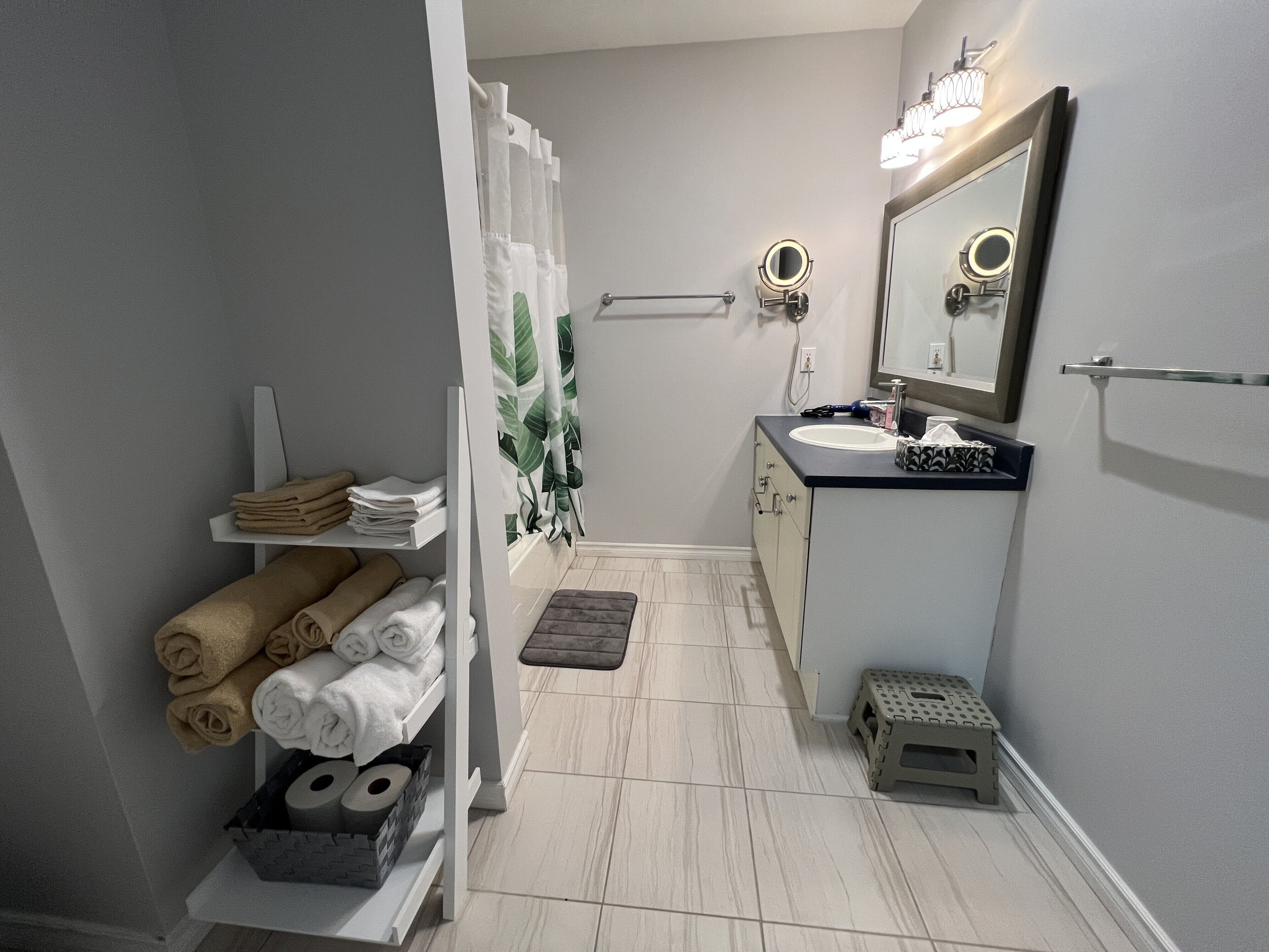 A bathroom with a sink, mirror, towel rack, and a shower curtain.
