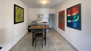 A narrow hallway with a dining table and chairs, a microwave, and cabinets in the background. - Casita Linda (Arecibo)