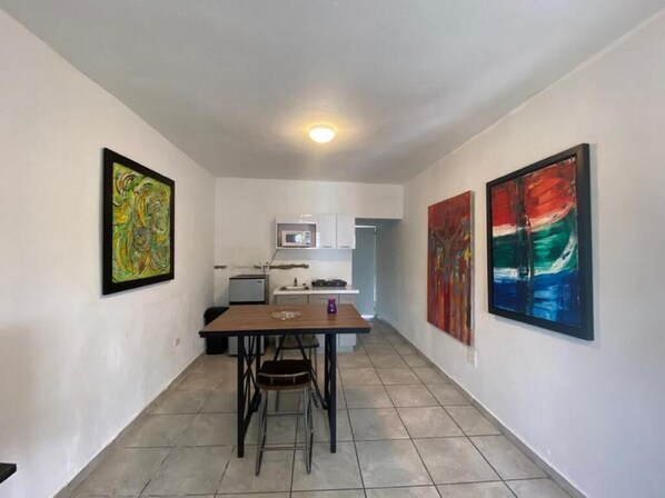 A narrow hallway with a dining table and chairs, a microwave, and cabinets in the background.