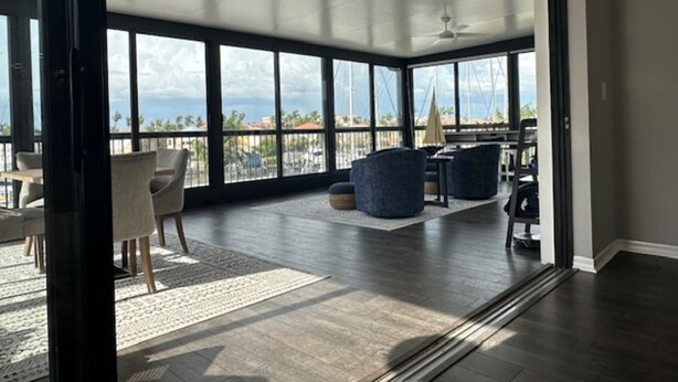 A spacious room with large windows, a ceiling fan, and a view of the ocean. - 3-bedroom condo w/ water views in phenomenal Burnt Store Marina in Punta Gorda
 (Punta Gorda)