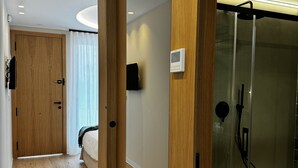 A modern hotel room with a wooden floor, a glass shower enclosure, and a wooden door. - Elegante Casa con Vistas al mar en la Playa #7 (Urbanova)