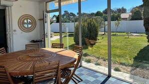 Comedor con una mesa redonda de madera y sillas, con grandes puertas correderas de vidrio que dan a un jardín.