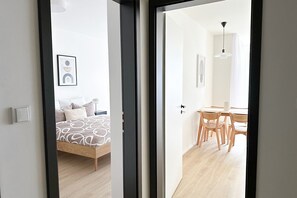 Cozy retreat with a neatly made bed, bedside table, and framed picture, set against a clean, white backdrop.