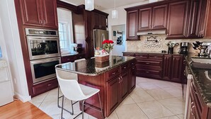 Una cocina moderna con armarios de madera oscura, electrodomésticos de acero inoxidable y una isla central con taburetes de bar.