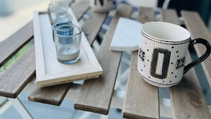A table with a white mug, a glass, and a candle holder. - New Studio in Belair with balcony (Luxembourg City)