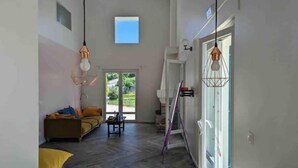 Un vaste espace de vie comprenant un canapé, une table basse et une vue sur l’extérieur grâce à une porte vitrée.