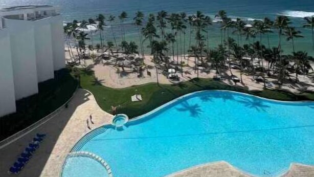 A resort with a swimming pool, a beach, and a view of the ocean.